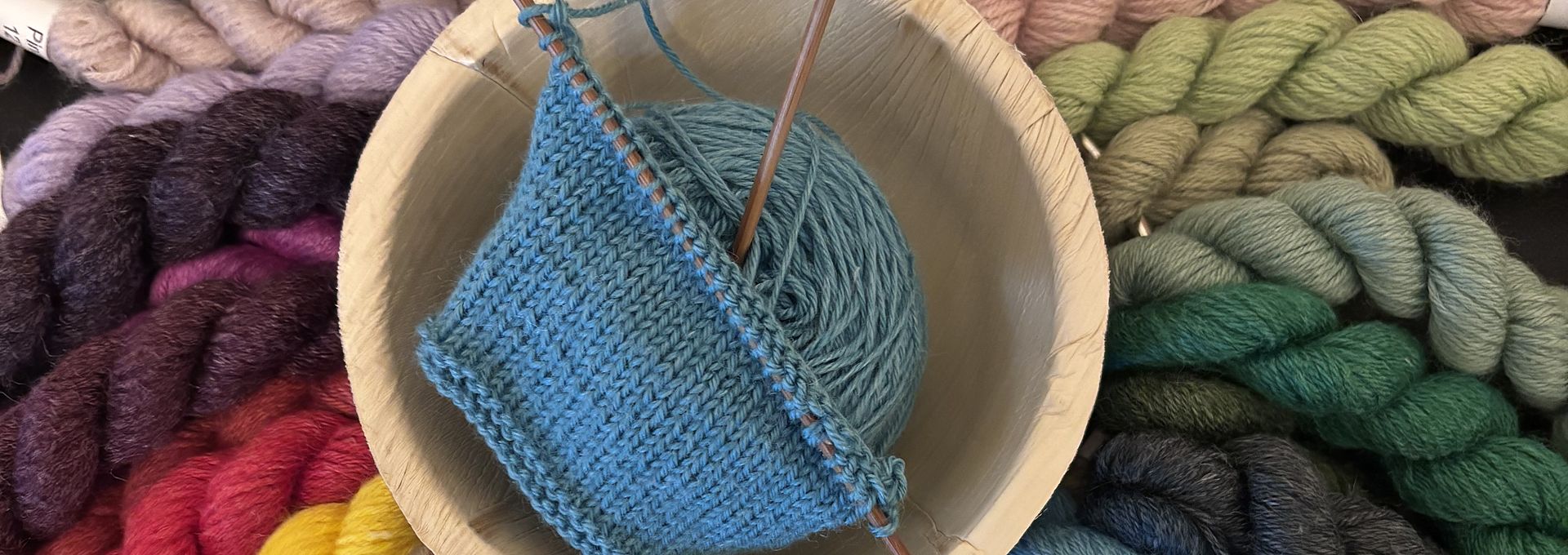 Échantillon tricoté dans un bol, entouré d’écheveaux colorés